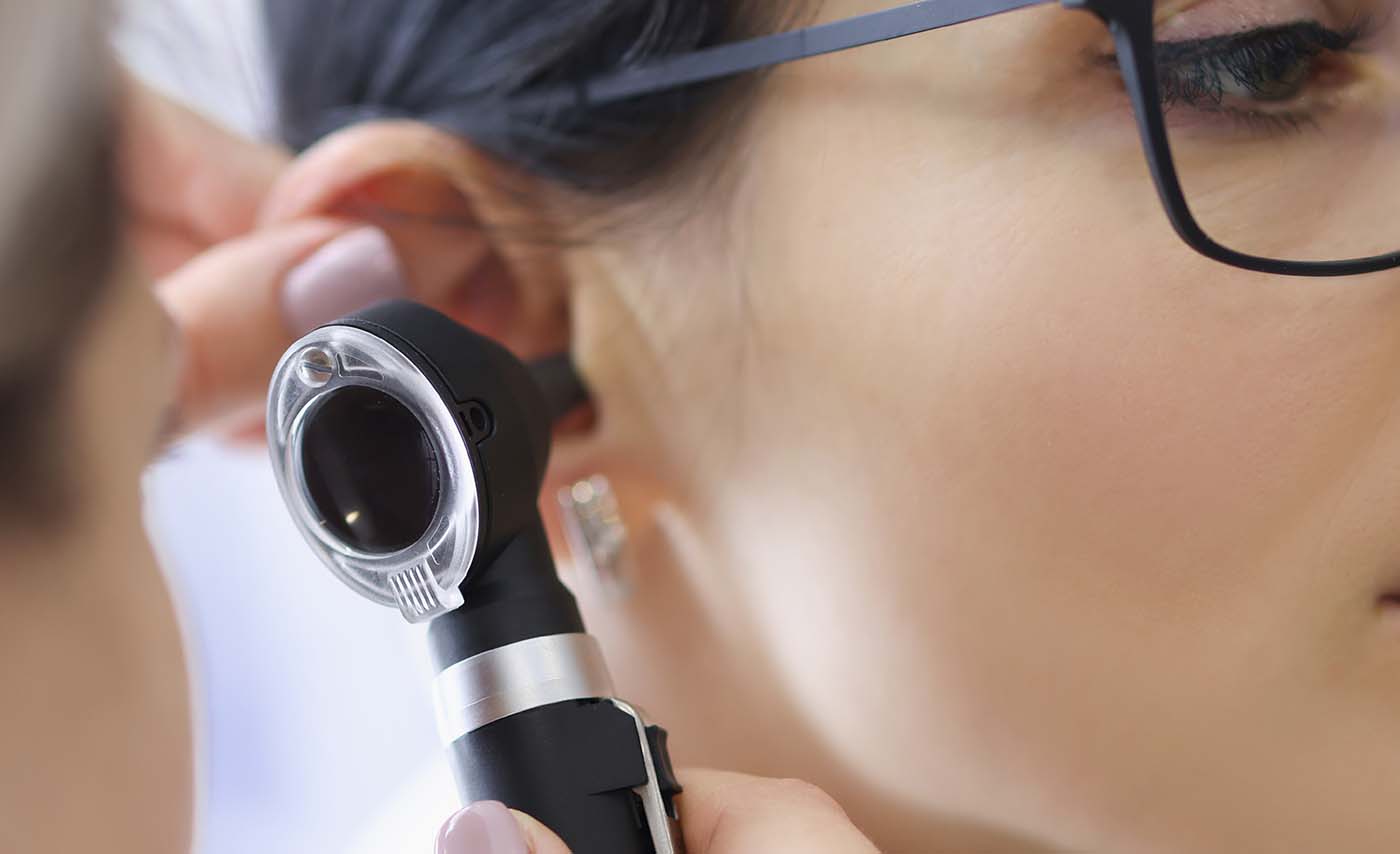 Lekarz laryngolog bada młodą kobietę za pomocą otoskopu